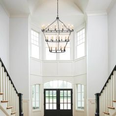 an elegant entryway with chandelier and wooden stairs leading up to the second floor