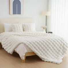 a bed with white blankets and pillows on top of it