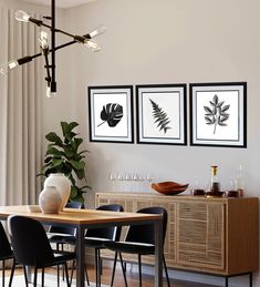 a dining room table with black chairs and framed pictures on the wall above it,