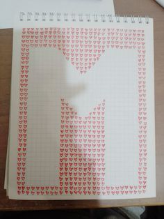 an open notebook with red hearts on it and a white paper cut out into the shape of a man's shirt