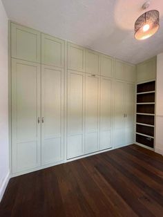 an empty room with white cabinets and wood floors