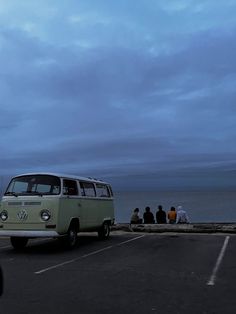 an old vw bus parked in a parking lot next to the ocean