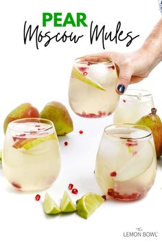 two glasses filled with white wine and fruit on the table next to some limes