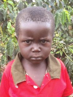 a young boy standing in front of some trees