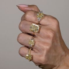 a woman's hand holding three rings with diamonds on each one and the other side