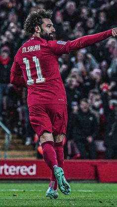 the soccer player is celebrating his goal in front of an excited crowd as he runs towards the ball