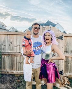 a man, woman and child posing for a photo in front of a wooden fence