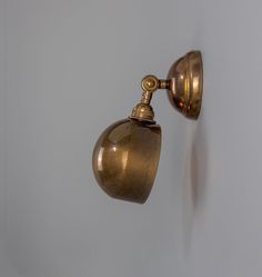 an old fashioned wall lamp on the side of a white wall with a gold finish