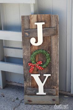 a wooden sign that says joy with a wreath on it