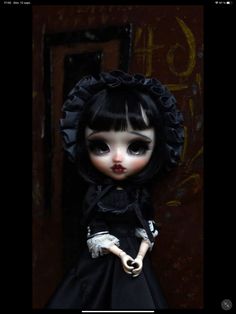 a doll with black hair and white eyes wearing a black dress is standing in front of a door