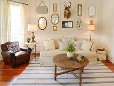 a living room filled with furniture and lots of mirrors on the wall above it's windows