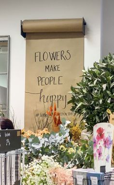 there is a sign that says flowers make people happy in front of some potted plants