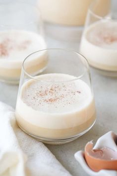 two glasses filled with liquid sitting on top of a table next to an egg shell