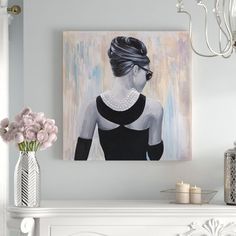 a painting is hanging on the wall next to a vase with pink flowers in it