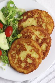 three potato and cheese patties on a white plate with lettuce, cucumber and tomato