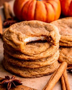 two cookies are stacked on top of each other next to cinnamon sticks and pumpkins