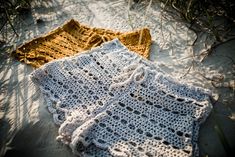 two crocheted blankets laying on the sand