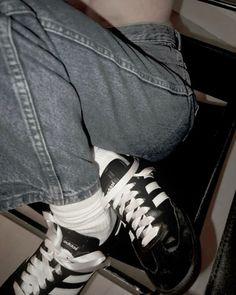 a person wearing black and white shoes sitting on a chair