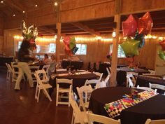 tables and chairs are set up with black tablecloths, balloons, and streamers