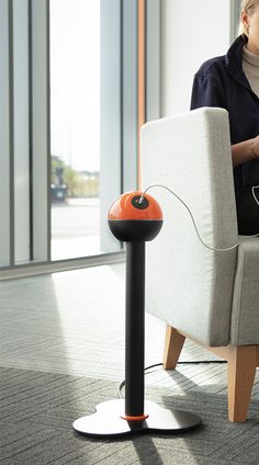 a woman sitting in a chair with an electronic device on her lap and headphones attached to the armrests