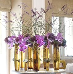 a group of vases filled with flowers sitting on top of a table next to a window