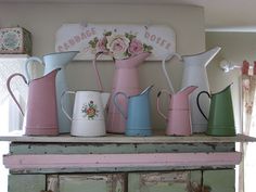 many different colored pitchers are on top of a dresser in a room with an old window