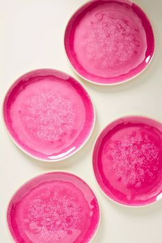 three pink plates sitting on top of a white table