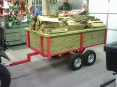 a red wagon filled with lots of wood in a garage next to a black motorcycle