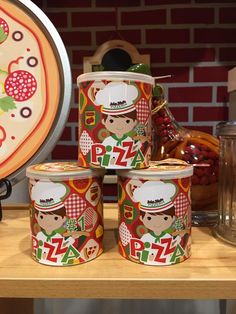 four tins of pizza sitting on top of a wooden table next to a clock