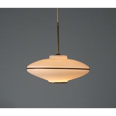 a white light hanging from a ceiling with a gray wall in the backround