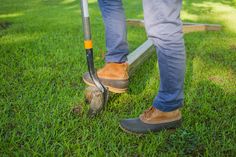 a man is standing in the grass with a lawn mower next to his foot