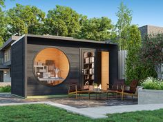 an outdoor living area with furniture and bookshelves in the center, surrounded by greenery