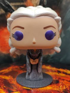 a close up of a figurine on a table with flames in the background