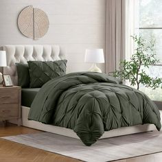 a bed with green comforter and pillows in a room