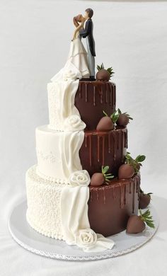 a wedding cake with chocolate frosting and strawberries on the top, topped with a bride and groom figurine