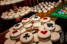 a table topped with lots of cookies covered in frosting and playing cards on top of them