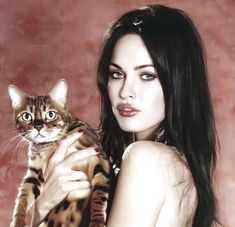 a woman is holding a cat in her arms and posing for the camera with long hair