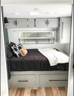 a bed in the middle of a room with white cabinets and black sheets on it