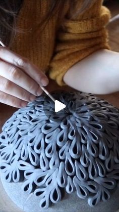 a woman is working on a sculpture with scissors