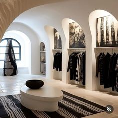 a room filled with lots of clothes on display next to arched walls and flooring