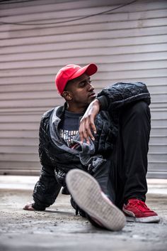 a man sitting on the ground wearing a red hat