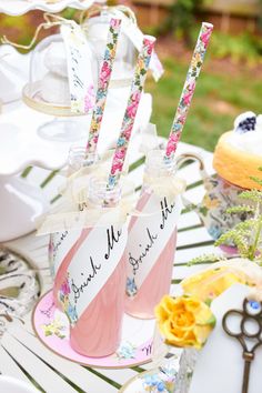 there are two pink cups with straws in them and some flowers on the table