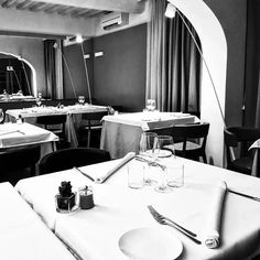 a black and white photo of a restaurant with tables set up for formal dinner,