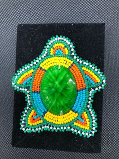 a beaded brooch sitting on top of a black surface