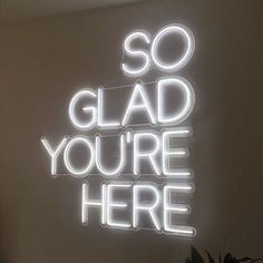 a neon sign that says so glad you're here