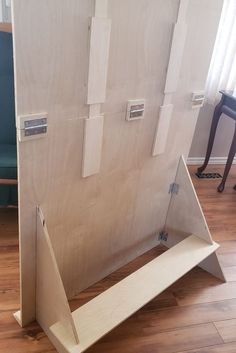 an unfinished piece of wood sitting on top of a hard wood floor next to a blue chair