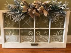 an old window decorated for christmas with snowflakes and pine cones