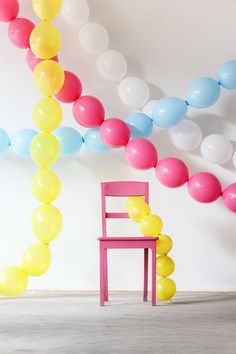 a pink chair sitting in front of a bunch of balloons