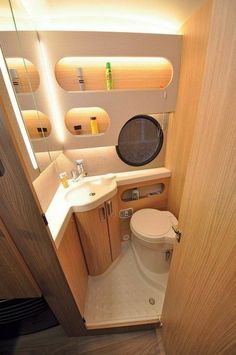 a bathroom with a toilet, sink and mirror in it's stall area next to a wooden door