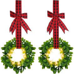 two christmas wreaths with lights hanging from the front and back, decorated with green leaves